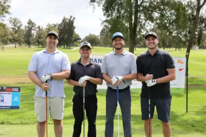 A foursome holding their clubs on the fairway