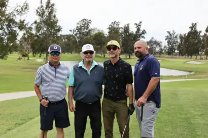 Four golfers standing together by a pond on the course