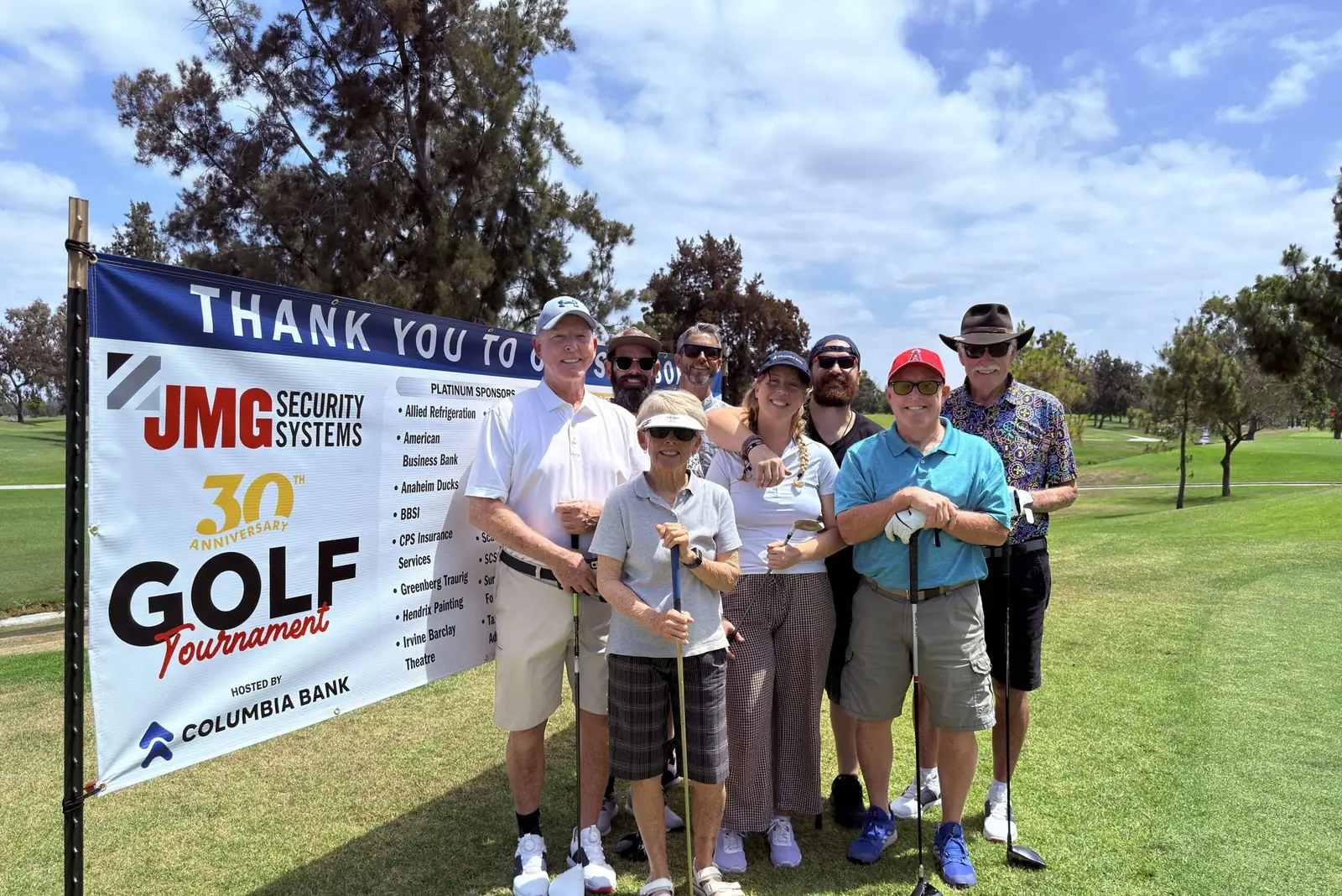 Golfers and guests in front of the thank-you banner at JMG's 30th Annual Benefit Golf Tournament, hosted by Columbia Bank