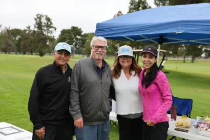 Four volunteers under a blue tent at the tournament
